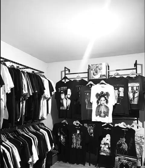 Racks and shelves of graphic tees and vintage pieces filling the corner of the archive's fitting room.
